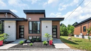 A modern two-story house with a brick facade, large windows, and a well-maintained garden. - Atlas | Familial | Piscine & Spa by Alchalet (Pont-Rouge)