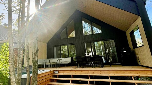 A modern house with a wooden deck, large windows, and a sloped roof. - ØM de Portneuf - Spa privé - Nature by Alchalet (Pont-Rouge)