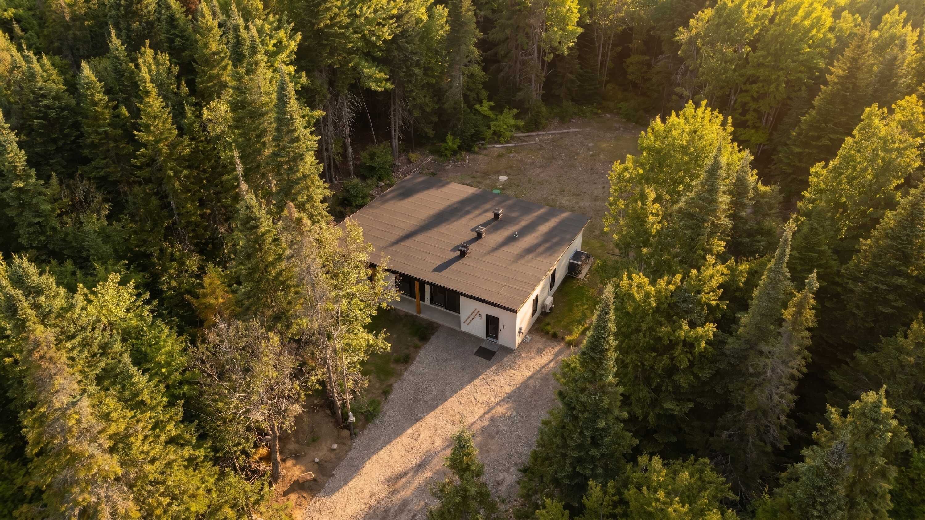 A modern house with a flat roof, surrounded by dense forest.