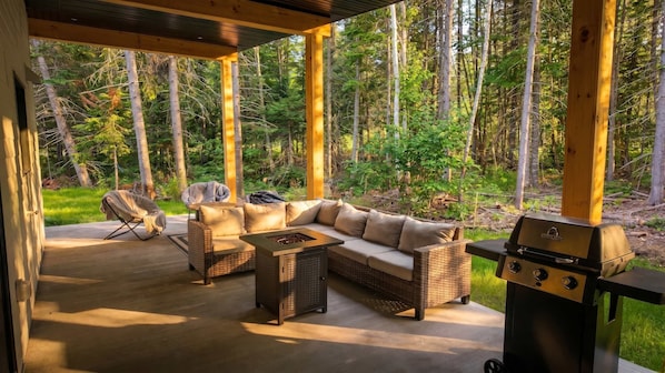 An outdoor patio with a sofa, chairs, and a grill.