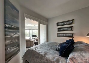 Ein Schlafzimmer mit einem Bett, einem Gemälde und drei gerahmten Bildern an der Wand.