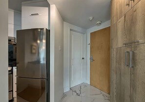 Eine moderne Küche mit einem Edelstahlkühlschrank, weißen Schränken und einer Holztür.