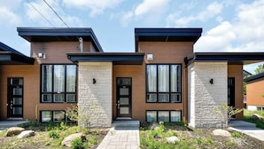 A modern two-story house with a brick facade, large windows, and a stone accent wall.