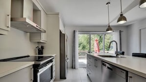 A modern kitchen with a central island, stainless steel appliances, and a large window providing a view of the outdoors.