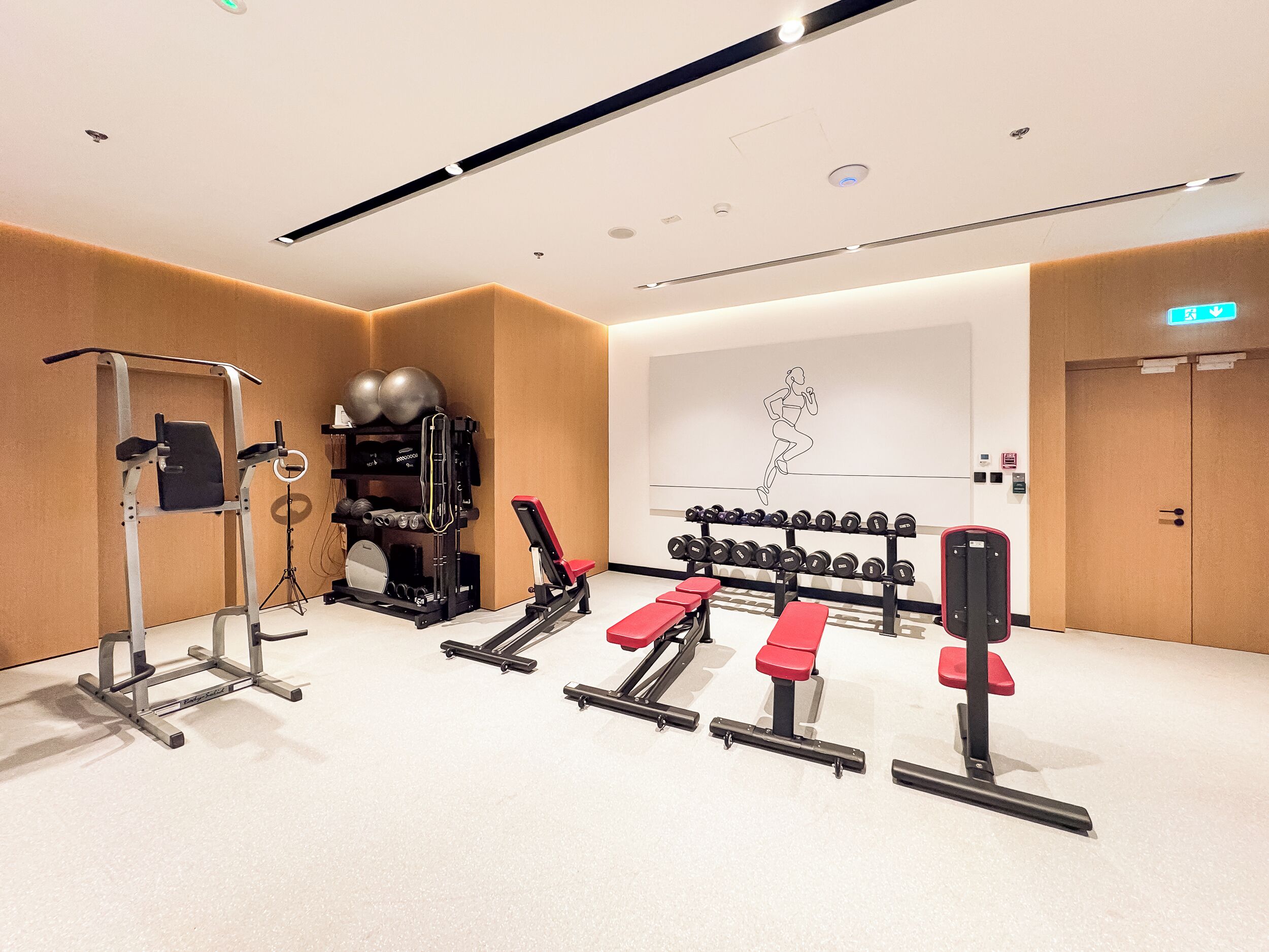 Un gimnasio moderno con equipo de ejercicio, un mural con una figura corriendo y un interior limpio y bien iluminado.