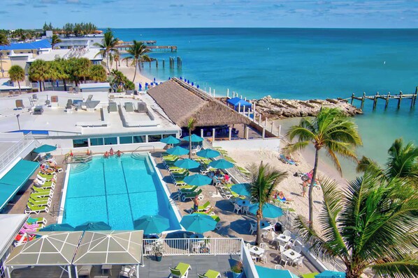 A resort with a swimming pool, beach area, and a pier.