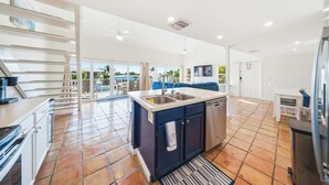 A spacious kitchen with a central island, a dining area with a blue sofa, and a view of the outdoors. - Sea Dreams on 9, 3 bedroom 3 bath 1/2 duplex, Private Pool in Key Colony Beach waterfront with 37 ft dockage and cabana club private membership, pool table and putting green. (Key Colony Beach)