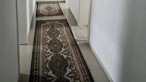 A narrow hallway with white walls, a black-framed mirror, and two patterned rugs on the floor. - Modern 3-room apartment near Frankfurt (Niddatal)
