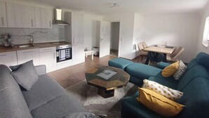 A modern living space with a kitchen, dining area, and a sofa. - Modern 3-room apartment near Frankfurt (Niddatal)