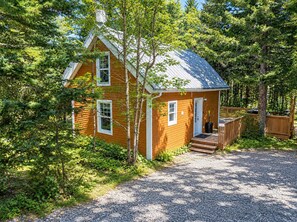 A wooden cabin with a sloped roof, a front porch, and a gravel driveway. - Spa & Relaxation | Sherwood 21 (Shannon)