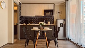 A compact kitchen with a dining area, featuring a microwave, refrigerator, and a small table set for two with chairs. - Escapada en Valparaíso (Valparaíso)