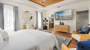 Un dormitorio con una cama grande, techo de madera, un televisor, un aparador y un espejo.