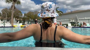 En swimmingpool med solstolar och palmer i bakgrunden.