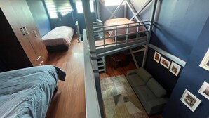 Una habitación compacta con literas, un sofá, una mesita y un armario.