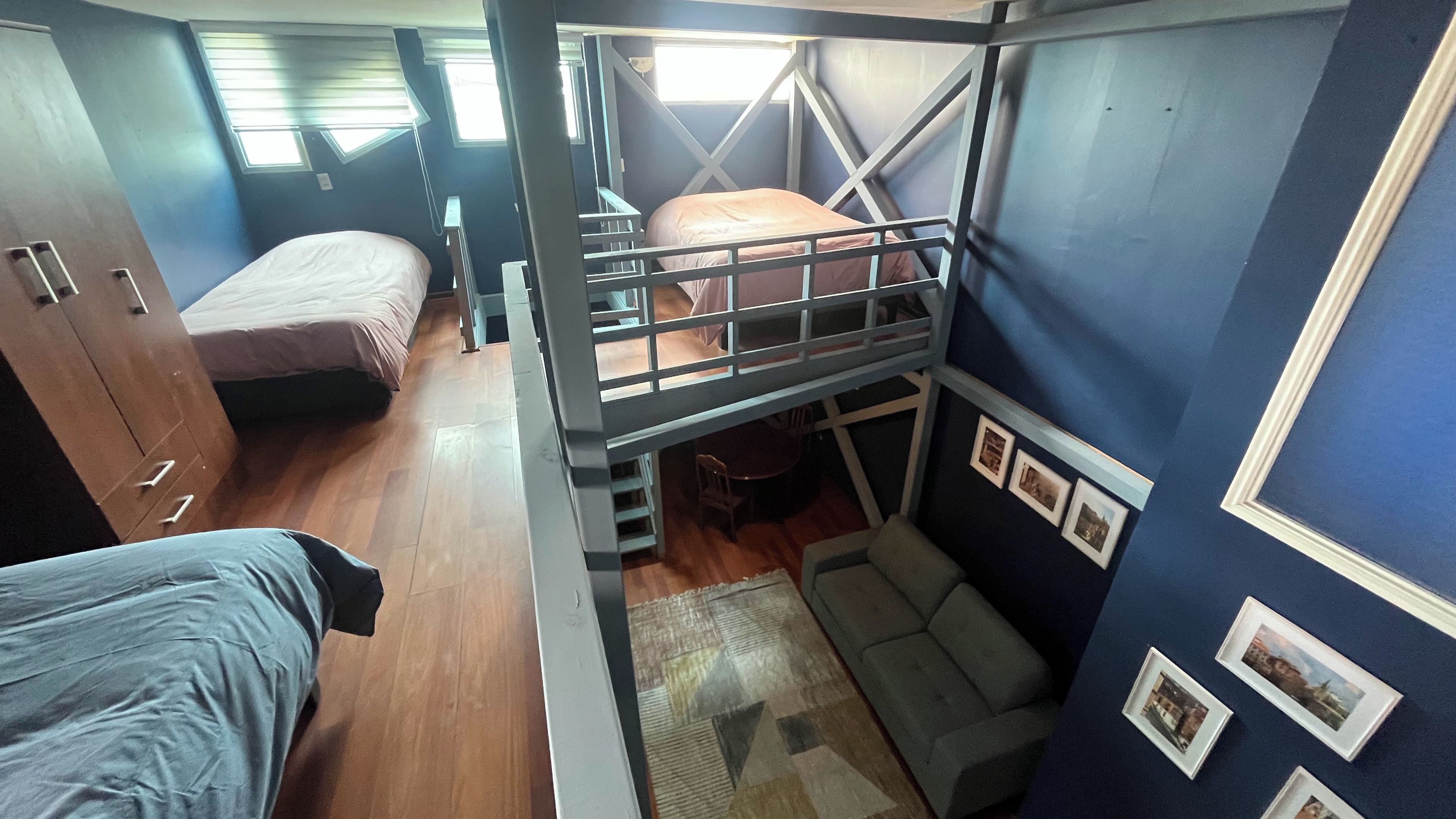 A compact room with bunk beds, a desk, and a small dining area.