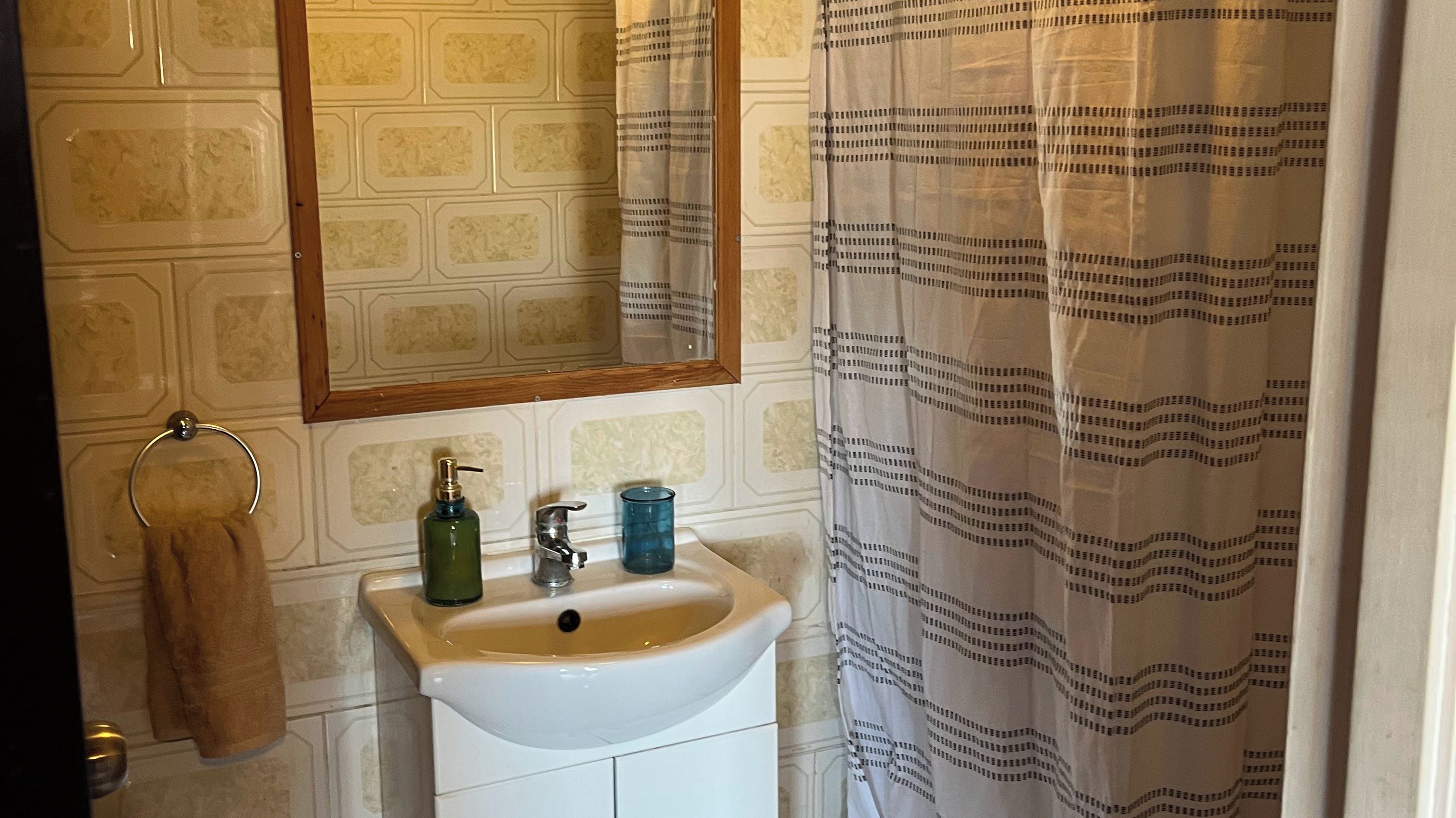 Un baño con un lavabo blanco, un espejo y una cortina de ducha.