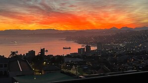Vista urbana al atardecer, con agua y montañas distantes.