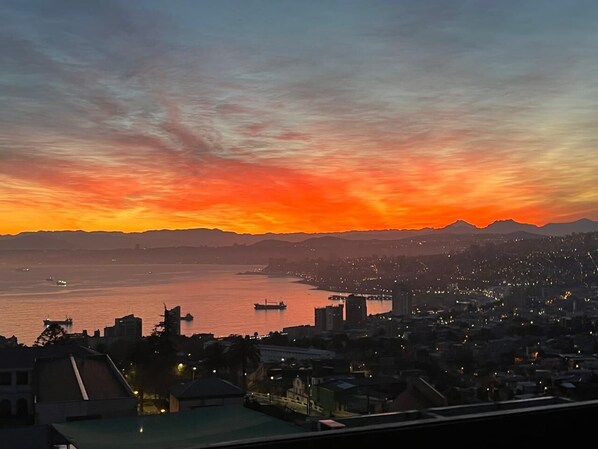 A cityscape at sunset with a view of the water and distant mountains.