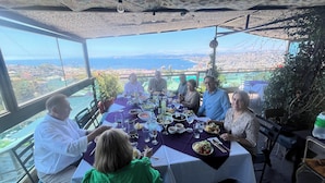 Un grupo de personas cenando en una mesa con vista a la ciudad.