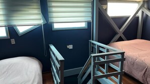 Un dormitorio con dos camas, una ventana y piso de madera.