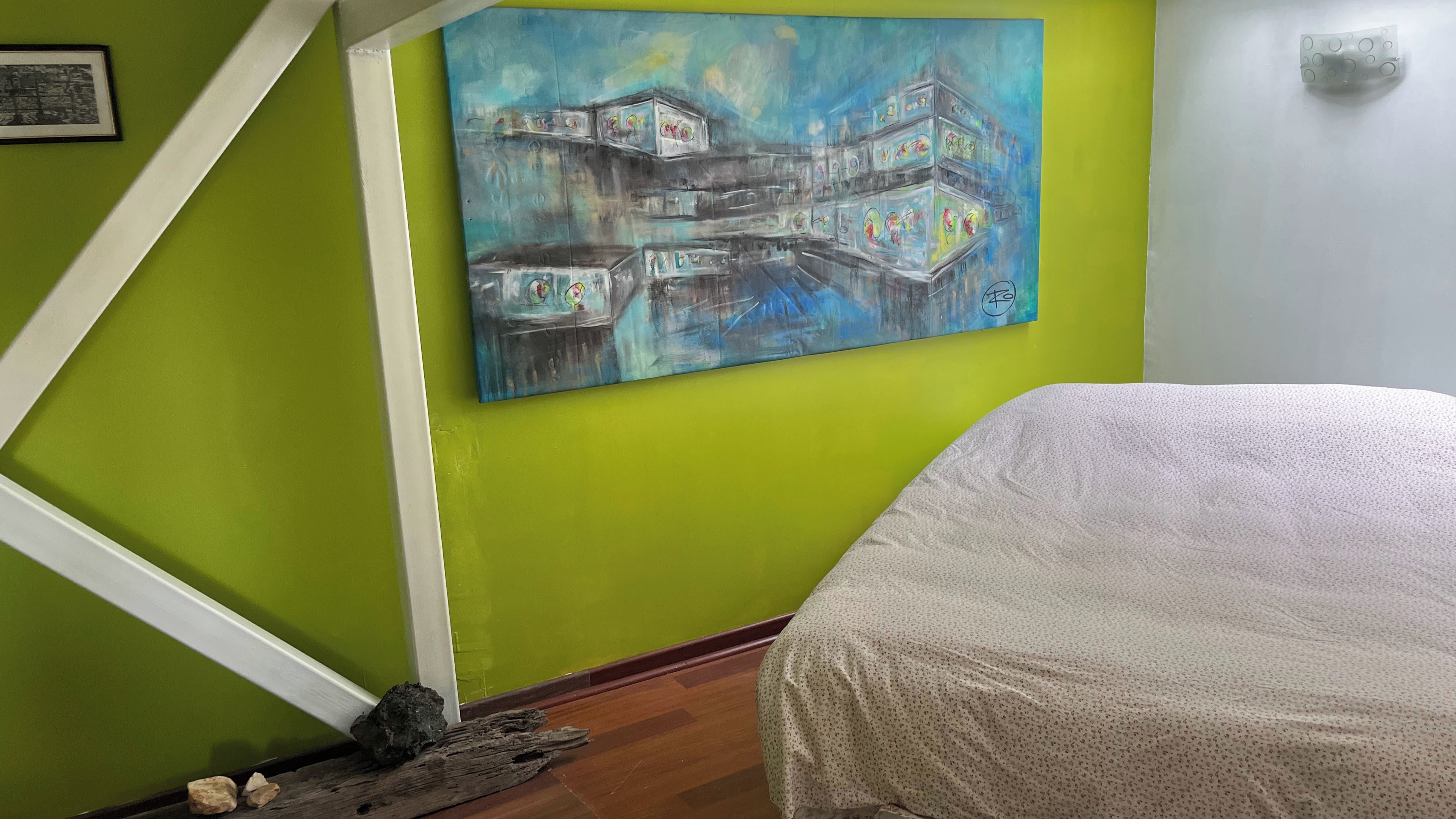 Une pièce avec un mur vert, un tableau, un lit et un plancher en bois.