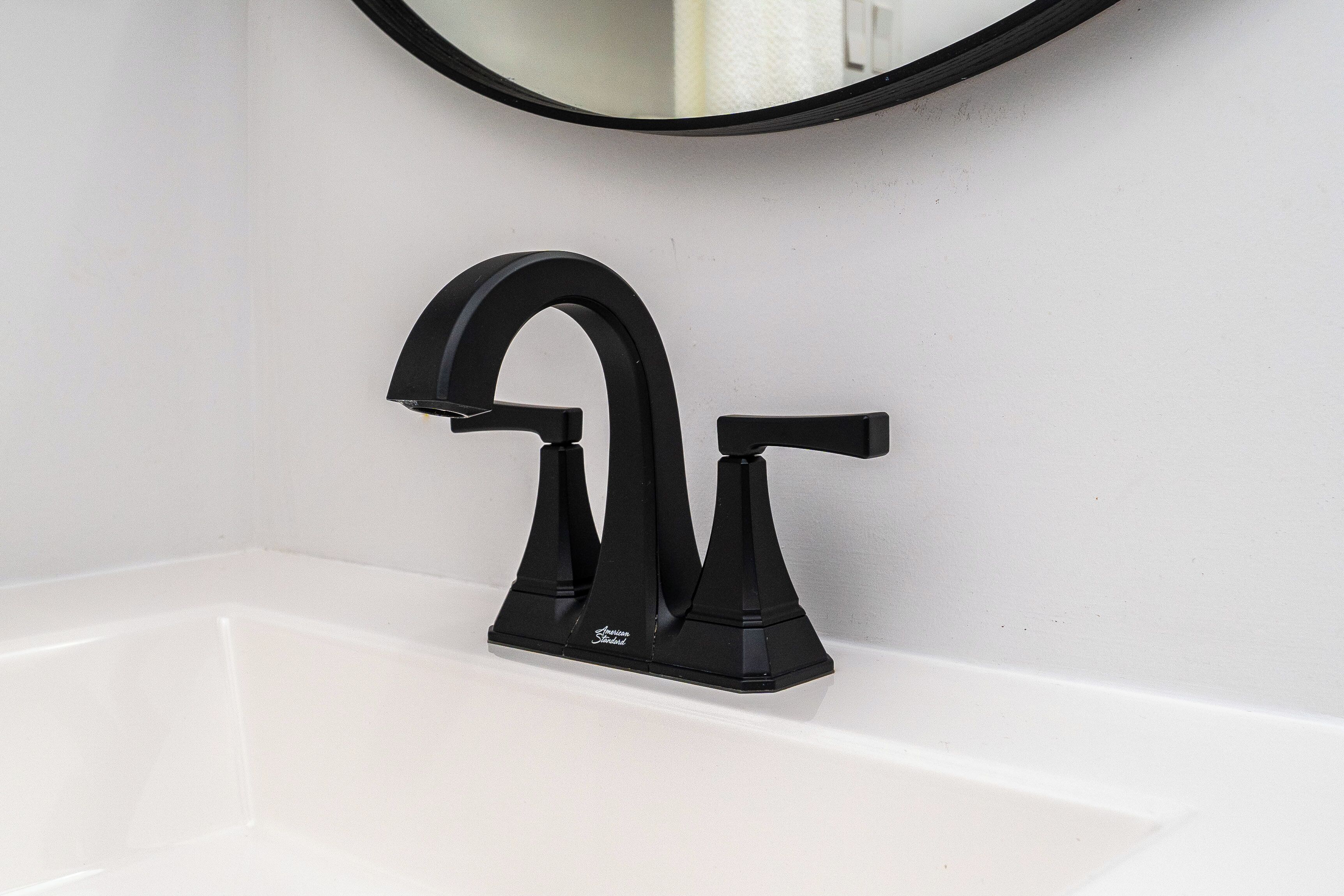 A black faucet with a single-handle design on a white sink.