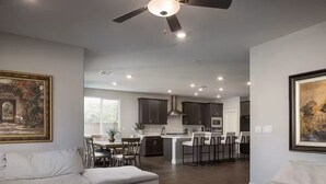 Un soggiorno moderno con divano, zona pranzo, cucina e ventilatore a soffitto.