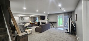 Ein Wohnzimmer mit Kamin, Sofa, Fernseher und einer Treppe.