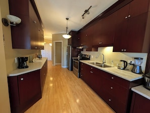 A kitchen with wooden cabinets, stainless steel appliances, and a marble countertop.