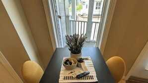 Uma mesa de jantar com um controle remoto, chaves e uma planta sobre um jogo americano.