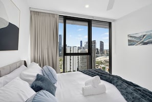 Une chambre d’hôtel avec un lit, une vue sur la ville et un tableau accroché au mur.