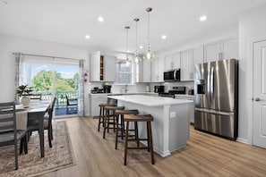 A modern kitchen with a central island, stainless steel appliances, and a dining area with a view.