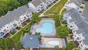Eine Vogelperspektive eines Wohnkomplexes mit einem zentral gelegenen Schwimmbad, umgeben von Häusern.