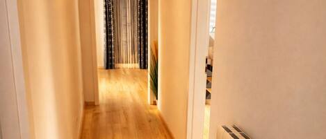 A hallway with wooden flooring, a radiator, and a door leading to a room.