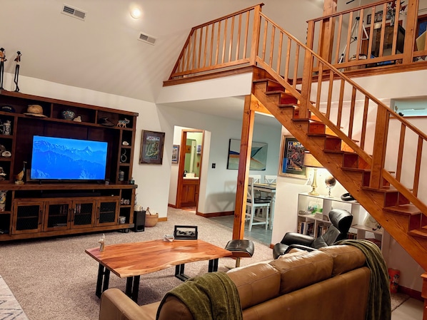 A spacious living room with a wooden staircase, a television, and a cozy seating area.