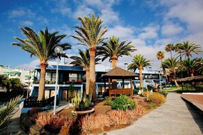 A hotel with palm trees, a gazebo, and a paved walkway. - Luxury Beach - 2 Bedroom Apartment (Maspalomas)