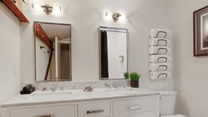 A bathroom with a double sink, a toilet, a mirror, and a towel rack. - Spacious 4BR Condo | Heart of Downtown Savannah (Savannah)