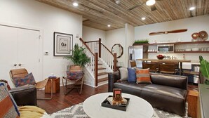 A modern living room with a staircase, a dining area, and a kitchen. - Spacious 4BR Condo | Heart of Downtown Savannah (Savannah)