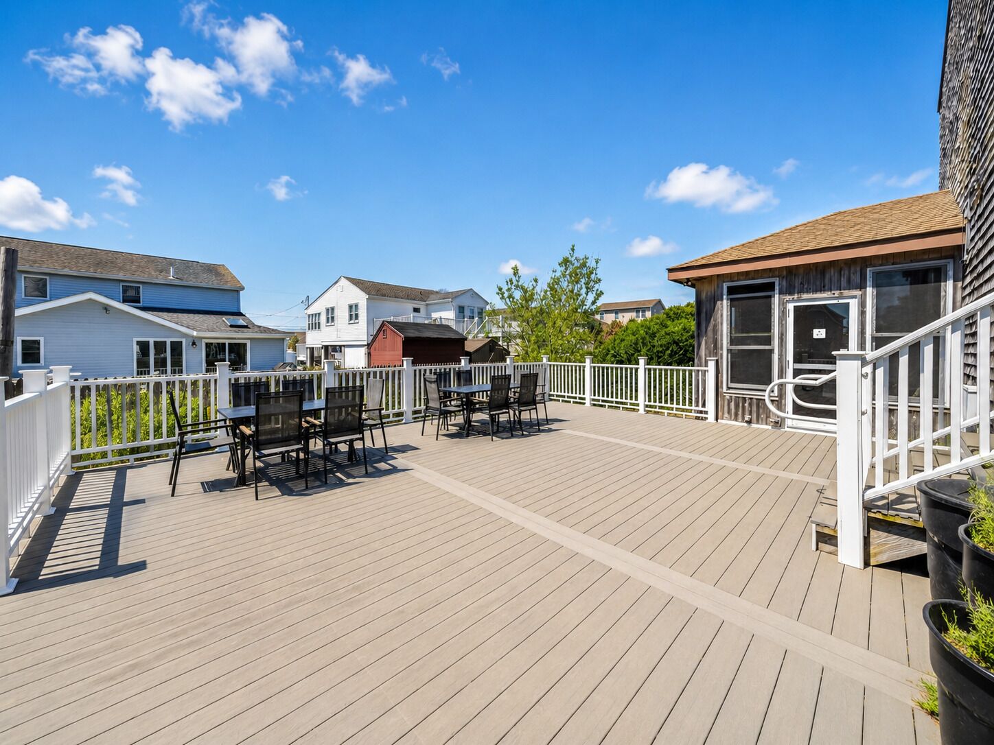 A wooden deck with outdoor seating and a white fence.