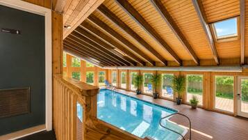 An indoor swimming pool with wooden beams and large windows.