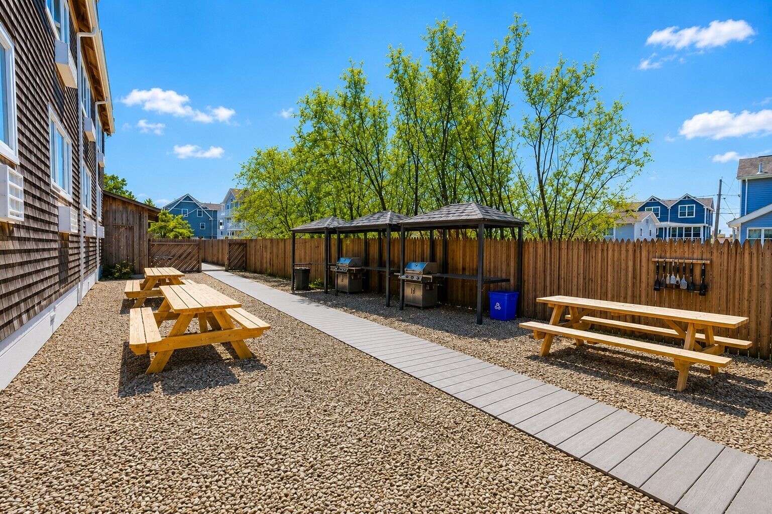 Un espace extérieur aménagé avec des tables de pique-nique, un barbecue et un coin salon abrité.