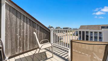 A balcony with a wooden fence, a white chair, and a view of a residential area.