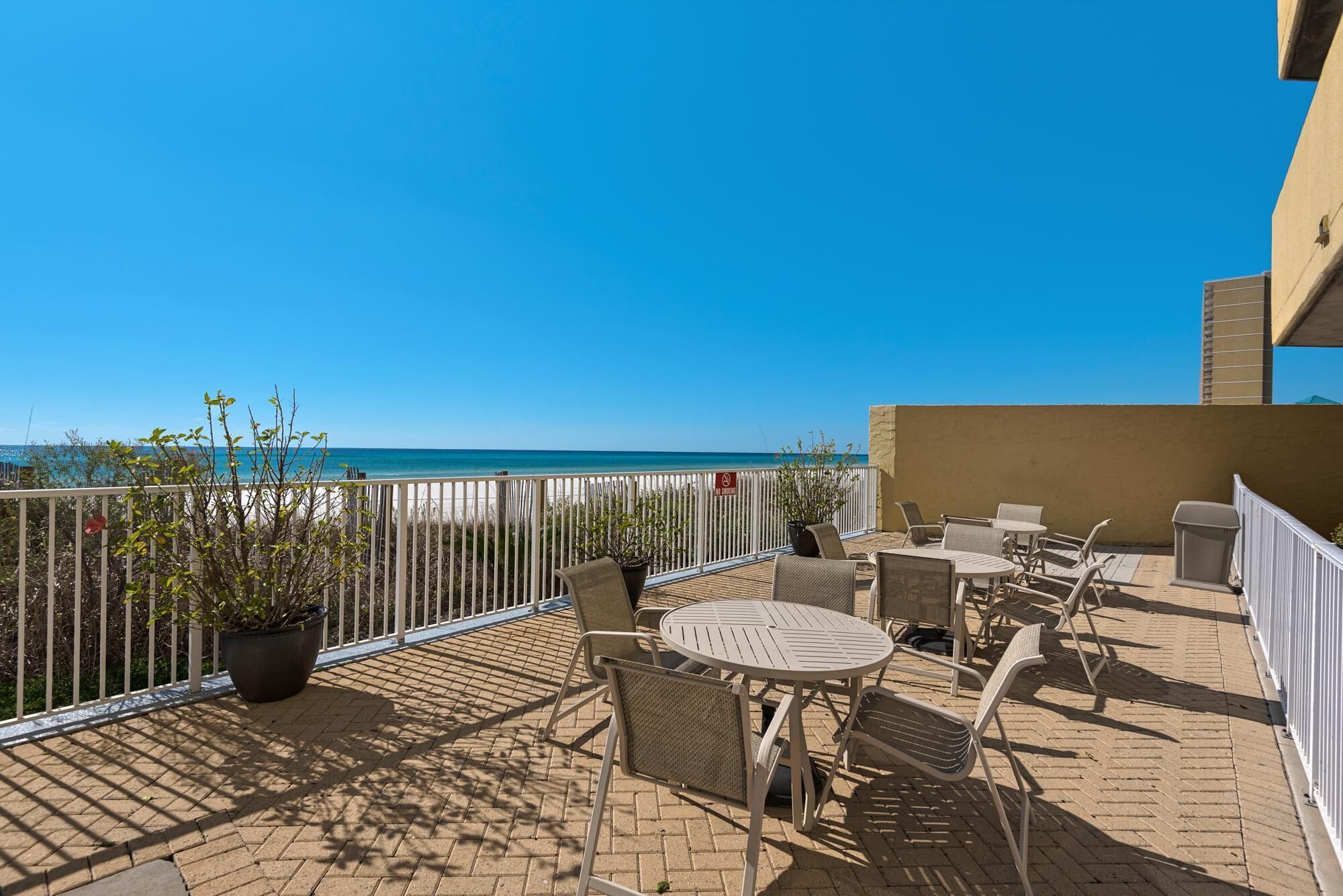 Une terrasse avec des places assises extérieures, une vue sur la mer et un panneau indiquant « Il est interdit de fumer ».