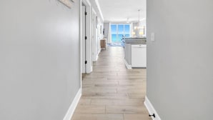 A hallway leading to a kitchen with a view of the ocean. - Emerald Isle 508 (Panama City Beach)