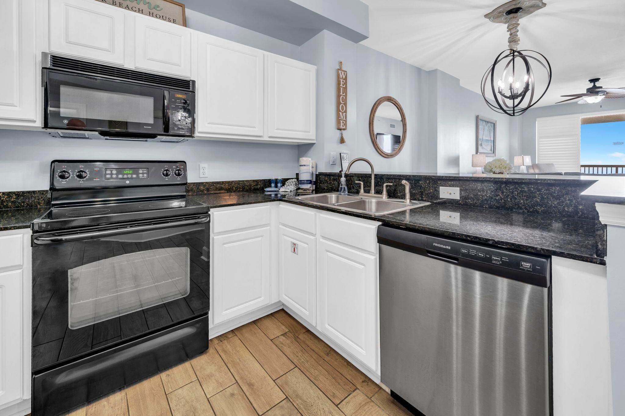 A kitchen with white cabinets, a stainless steel dishwasher, a microwave, and an oven.