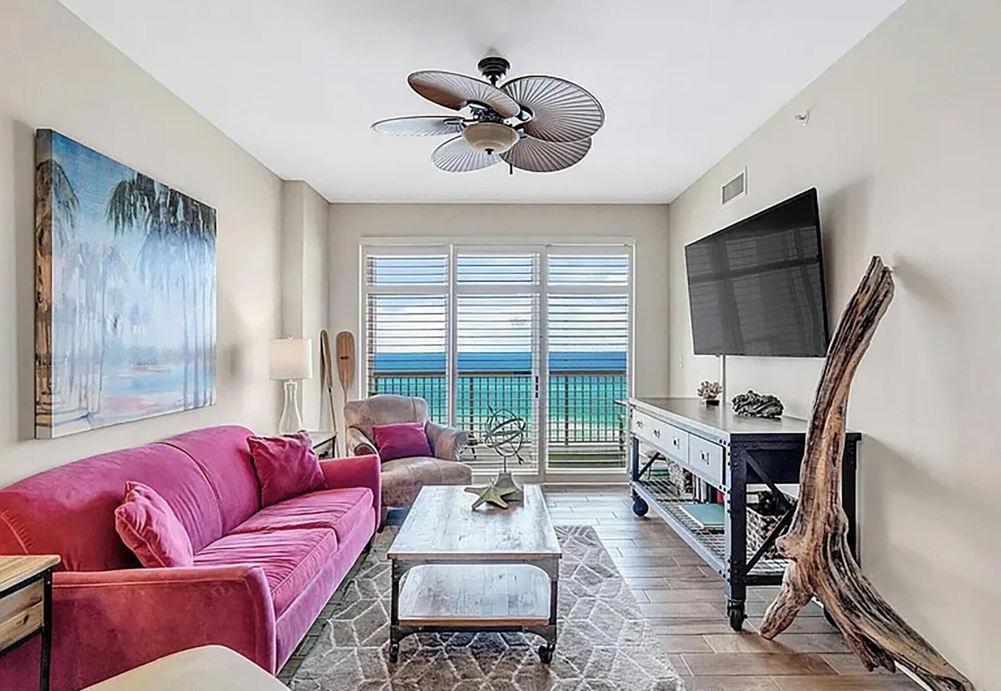 A living room with a sofa, coffee table, TV, and a balcony with a view.
