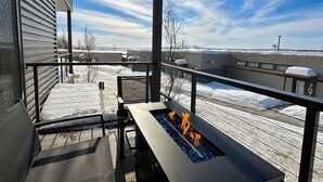A balcony with a fire feature, a view of the sky, and a snowy landscape. - Modern Hideaway with Private Terrace in Downtown (Anchorage)