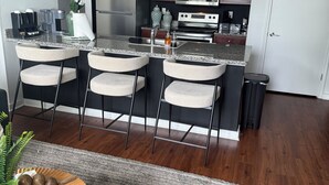 Une cuisine moderne avec un îlot central, des tabourets de bar, une horloge et un four à micro-ondes.
