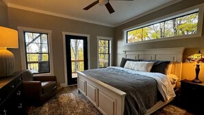 Une chambre à coucher comprenant un lit, une commode, une table de chevet, une lampe et un ventilateur de plafond.