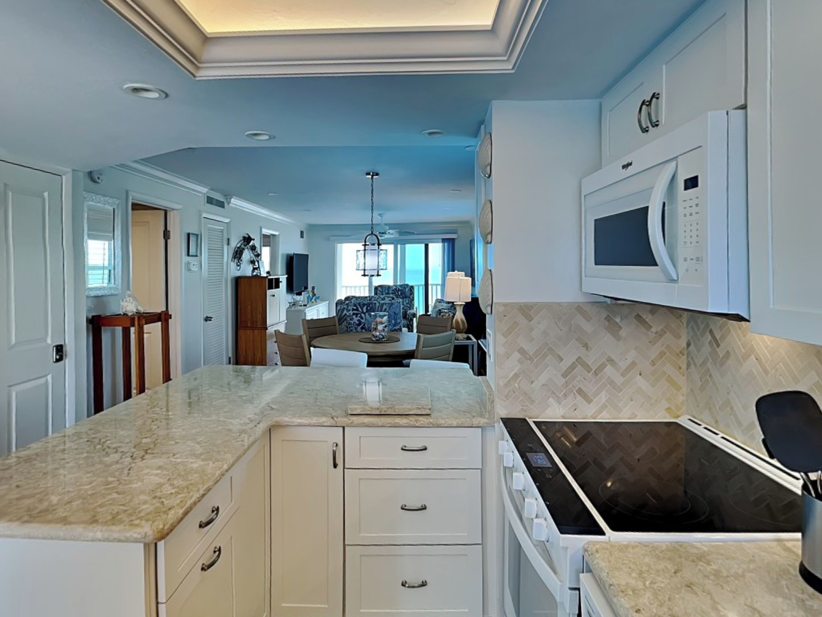 A modern kitchen with a central island, built-in microwave, and a dining area with a view.